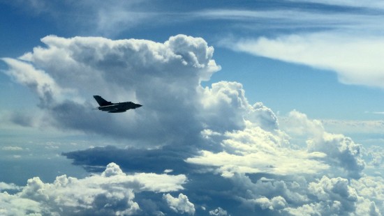 Image black airplane flying under white clouds during daytime