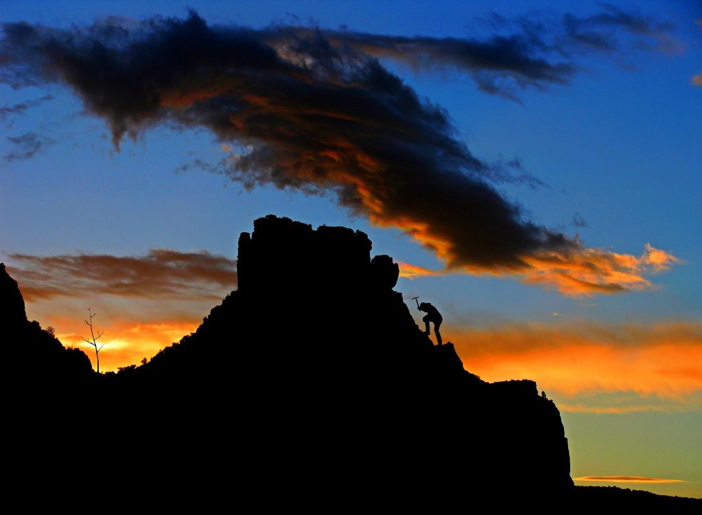 silhouette of people on rock formation during sunset