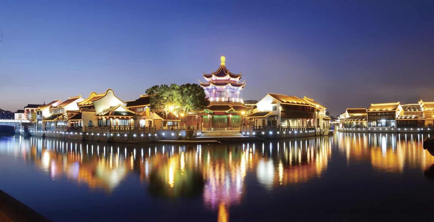 brown and white temple near body of water during night time