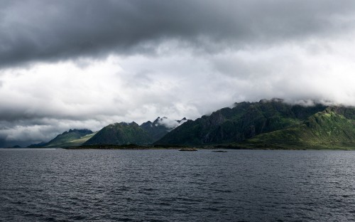 Image green mountain beside body of water under cloudy sky during daytime