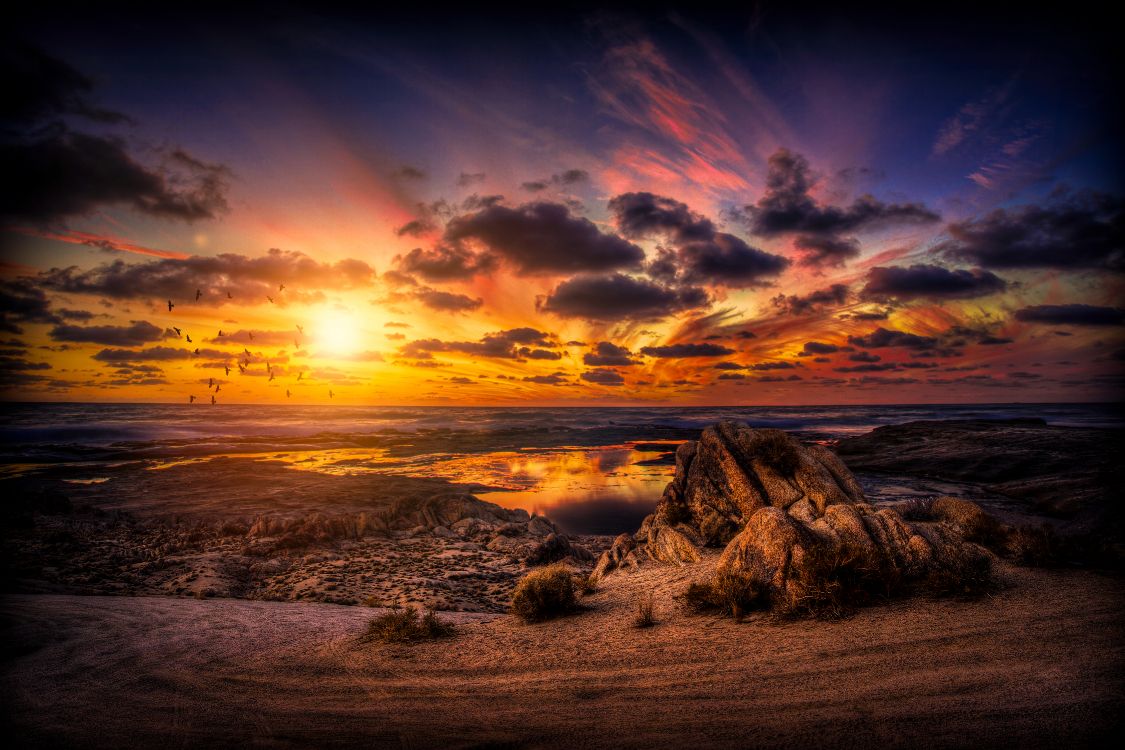 brown rock formation on sea shore during sunset