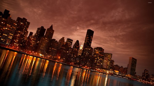 Image city skyline across body of water during night time