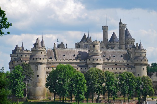 Image gray concrete castle surrounded by green trees under white clouds during daytime