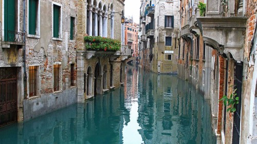 Image river between concrete buildings during daytime