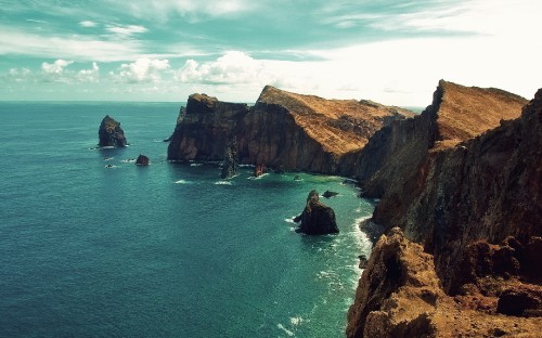 Image brown and green mountain beside blue sea under blue sky during daytime