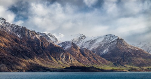 Image snow covered mountain near body of water during daytime