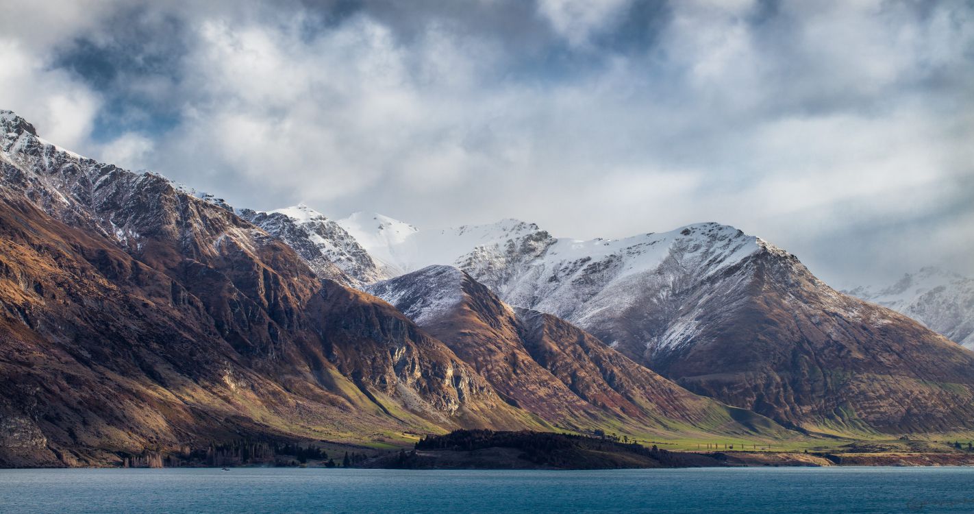 snow covered mountain near body of water during daytime