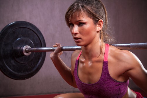 Image woman in pink tank top holding barbell