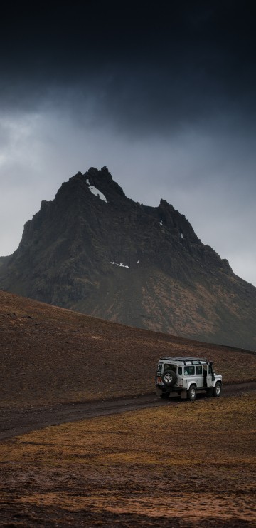 Image white suv on brown field near mountain under white sky during daytime