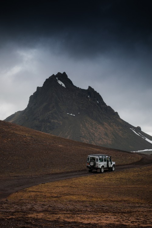 Image white suv on brown field near mountain under white sky during daytime