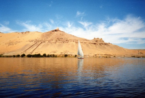 Image white sailboat on sea near brown mountain under blue sky during daytime