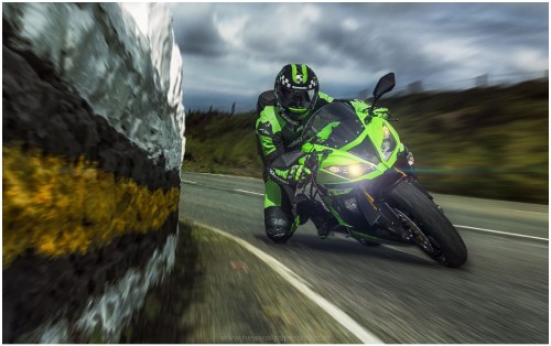 Image man in green and black motorcycle suit riding on black and green sports bike