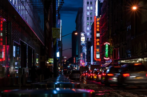 Image cars on road between high rise buildings during night time