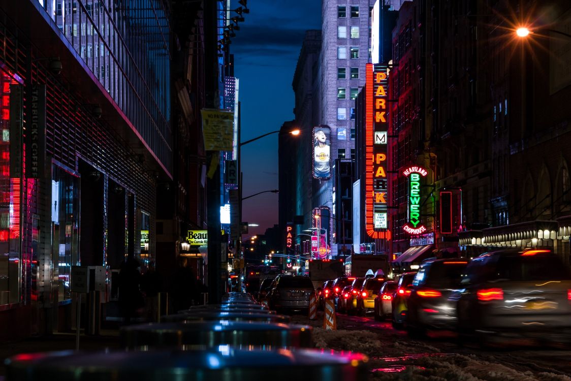 cars on road between high rise buildings during night time