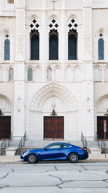 Image blue coupe parked beside white concrete building during daytime