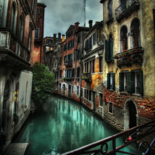 Image river between concrete buildings during daytime