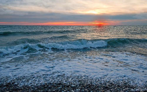 Image ocean waves crashing on shore during sunset