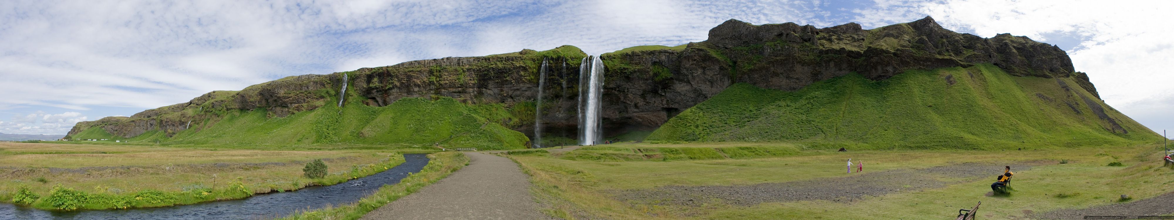 waterfalls on green grass field under white clouds during daytime