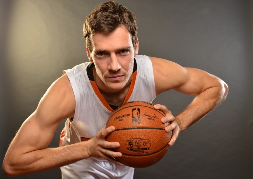 Image man in white tank top holding brown basketball