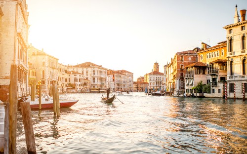 Image man riding on boat on water near buildings during daytime