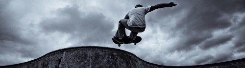 Image man in gray hoodie and black pants jumping on gray rock