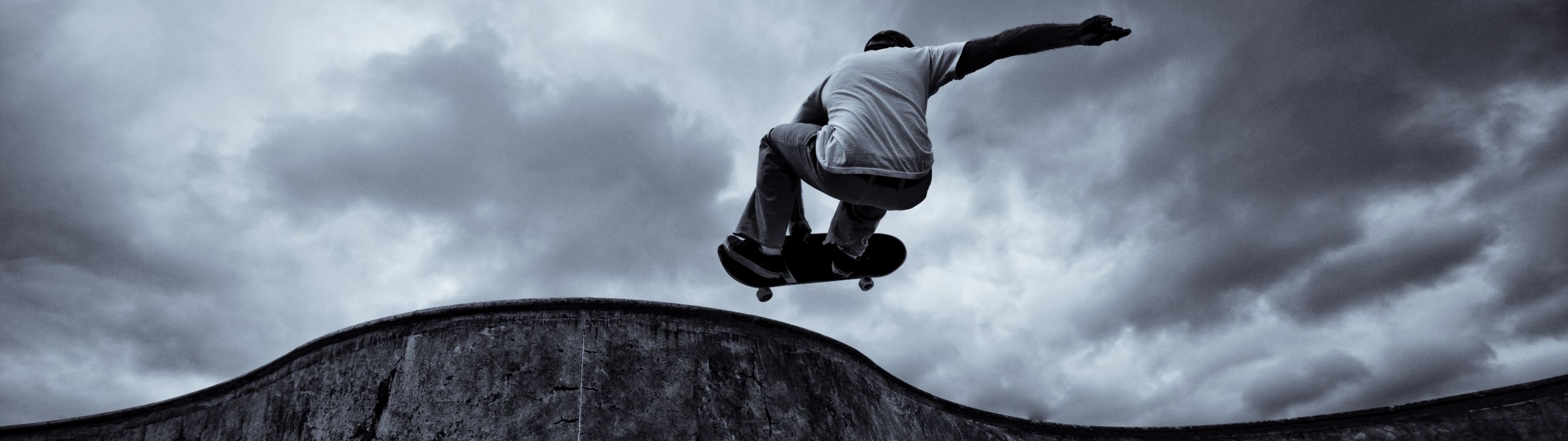 man in gray hoodie and black pants jumping on gray rock