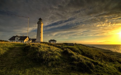 Image white lighthouse on green grass field under blue sky during daytime