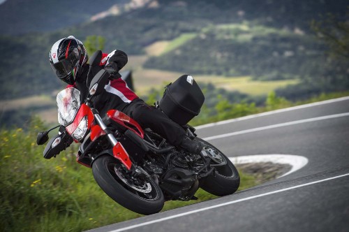 Image man in black and red motorcycle suit riding on red sports bike on road during daytime