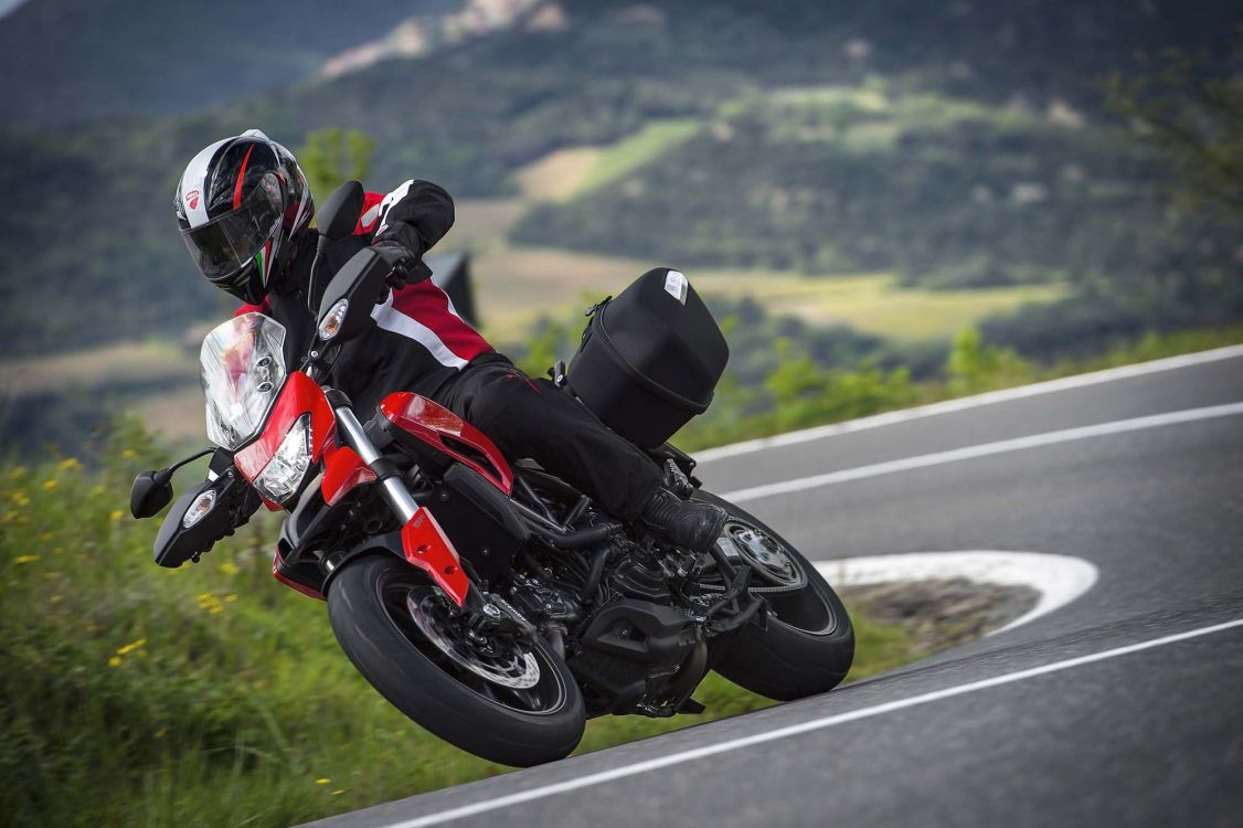 man in black and red motorcycle suit riding on red sports bike on road during daytime