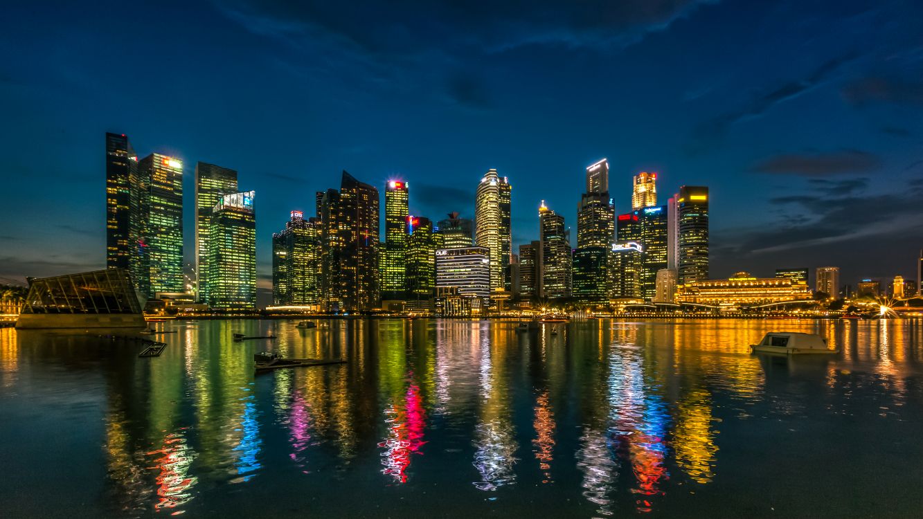 city skyline across body of water during night time