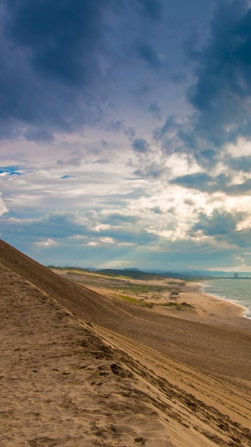 Image brown sand near body of water under blue sky and white clouds during daytime
