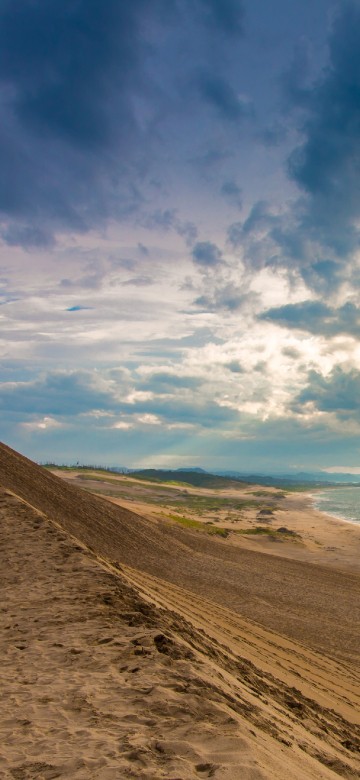 Image brown sand near body of water under blue sky and white clouds during daytime