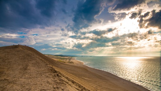 Image brown sand near body of water under blue sky and white clouds during daytime