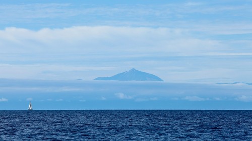 Image body of water near mountain under blue sky during daytime