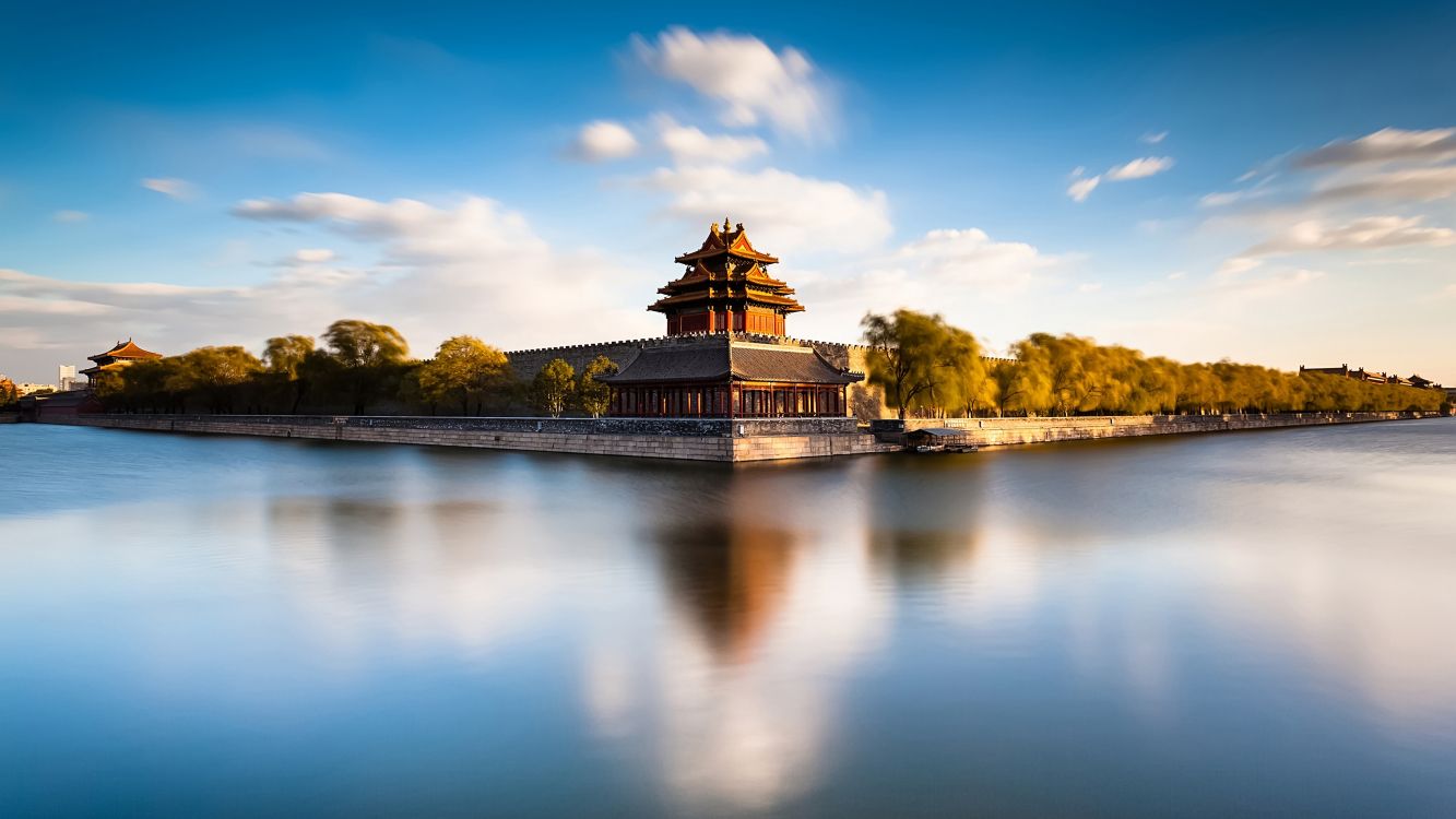 brown concrete building near body of water under blue sky during daytime