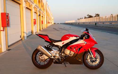 Image red and black sports bike parked on the side of the road during daytime