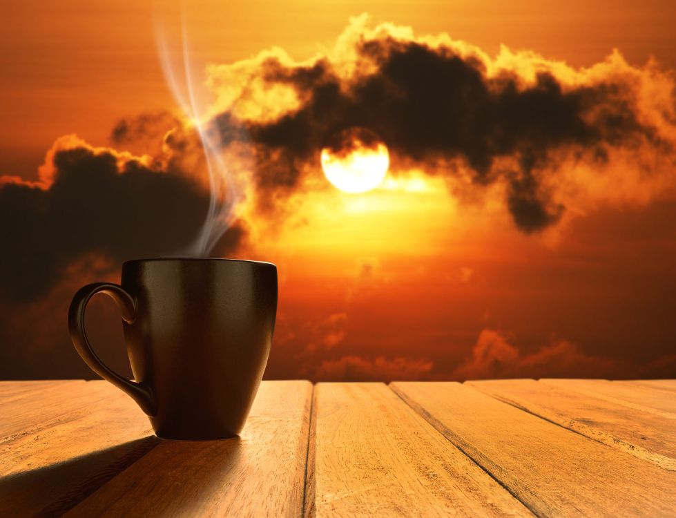 white ceramic mug on brown wooden table during sunset