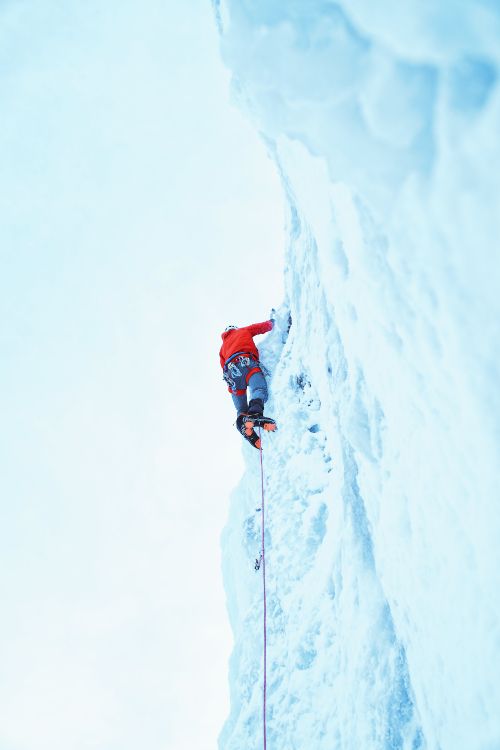 Persona en Chaqueta Roja y Pantalón Azul en la Montaña Cubierta de Nieve Durante el Día. Wallpaper in 4000x6000 Resolution