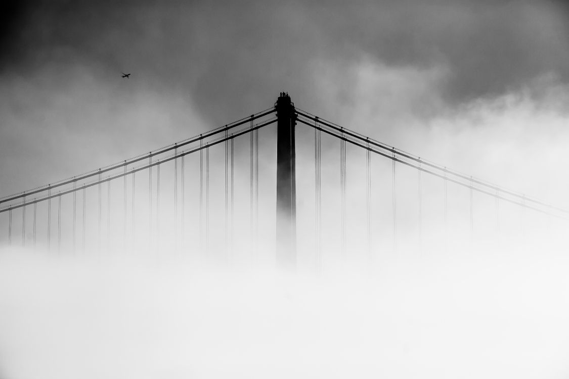 grayscale photo of bridge under cloudy sky