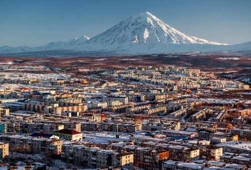 Image aerial view of city buildings near snow covered mountain during daytime