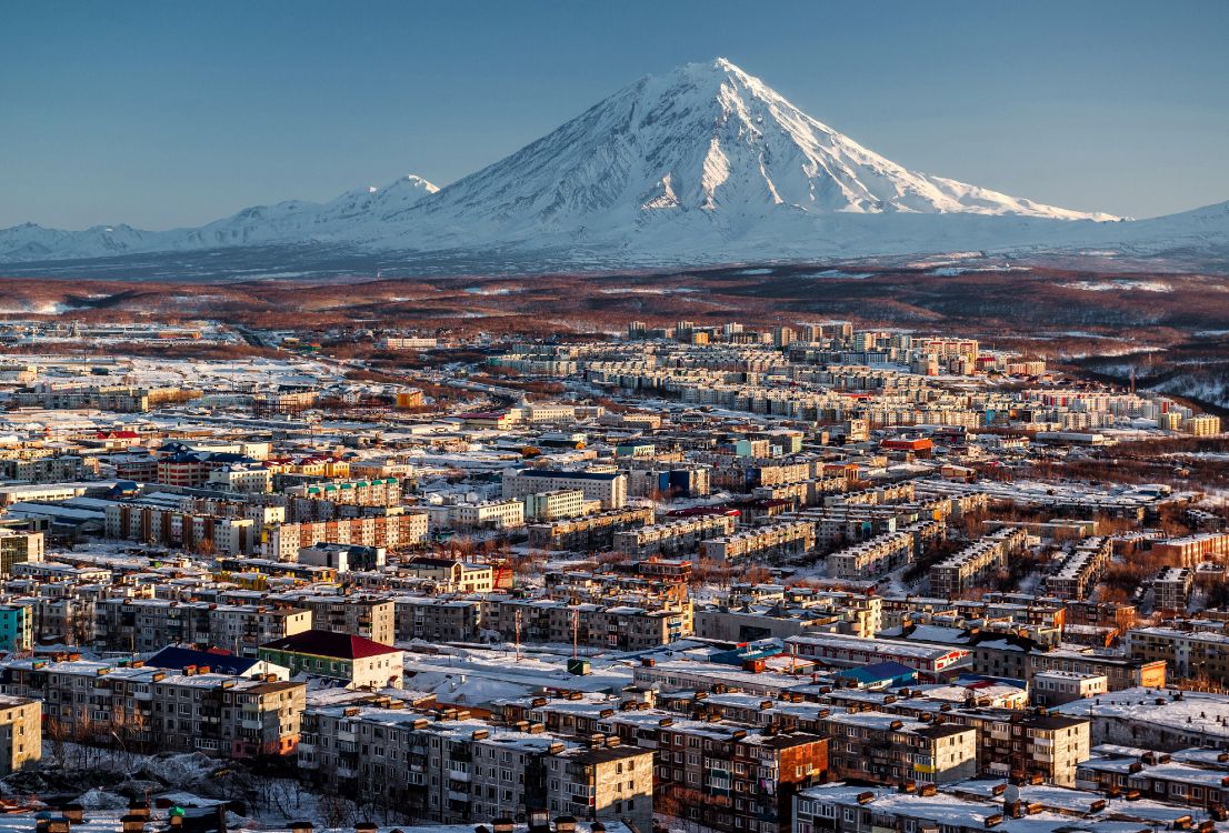 aerial view of city buildings near snow covered mountain during daytime