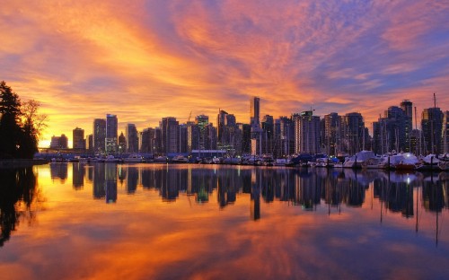 Image city skyline across body of water during sunset