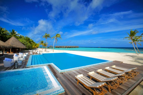 Image brown wooden lounge chairs on blue swimming pool during daytime