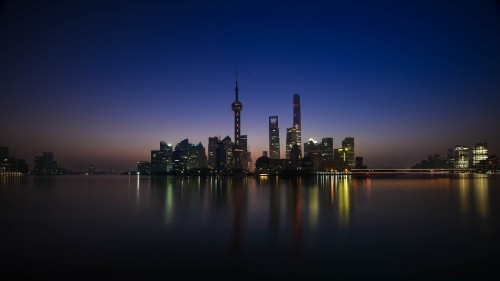 Image city skyline across body of water during night time