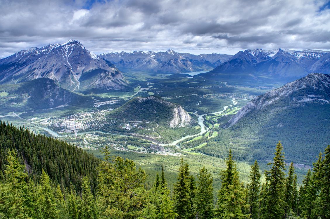 green trees and mountains under white clouds and blue sky during daytime