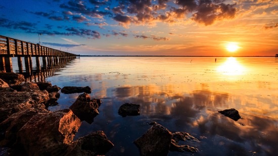 Image brown wooden dock on body of water during sunset