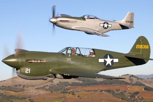 Image green and black fighter plane flying over brown field during daytime