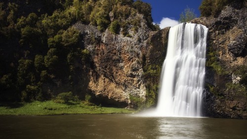 Image waterfalls near green trees under blue sky during daytime