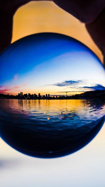 Image person holding blue ball reflecting the sun