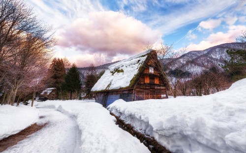 Image brown wooden house on snow covered ground under white clouds and blue sky during daytime